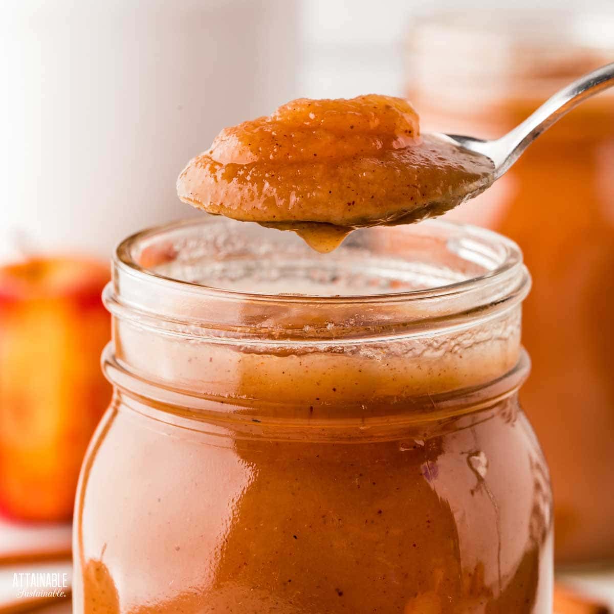 Spoon full of apple butter over an open jar.