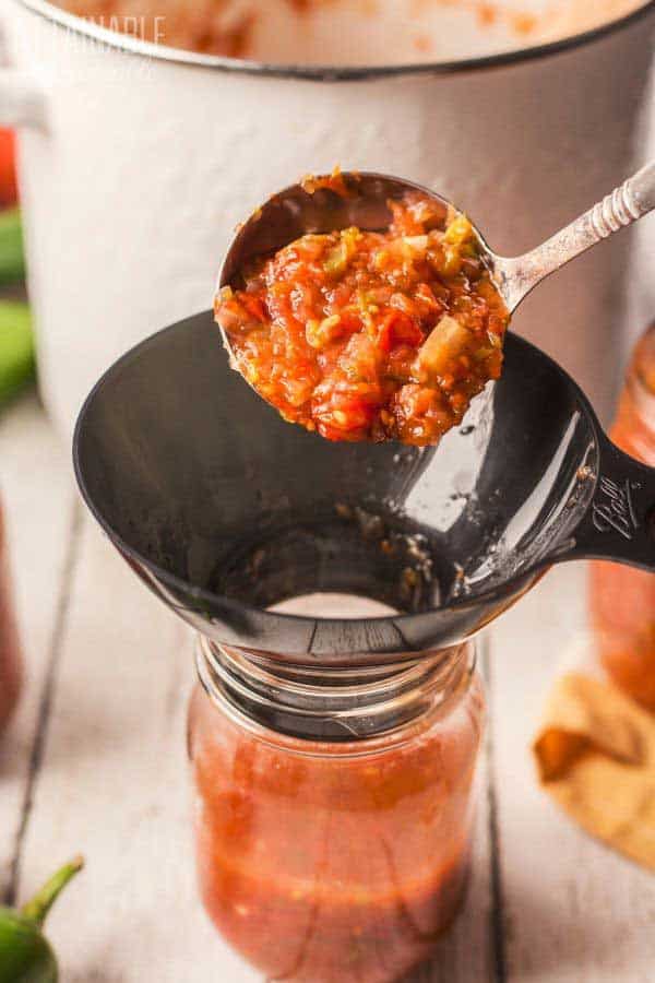 ladling salsa into a canning jar