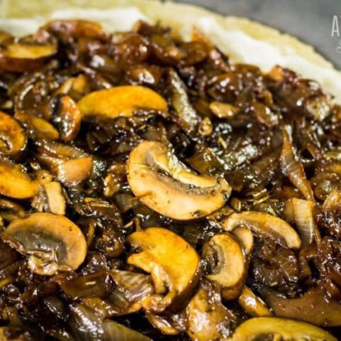 mushrooms and onions spread on a flat pie crust