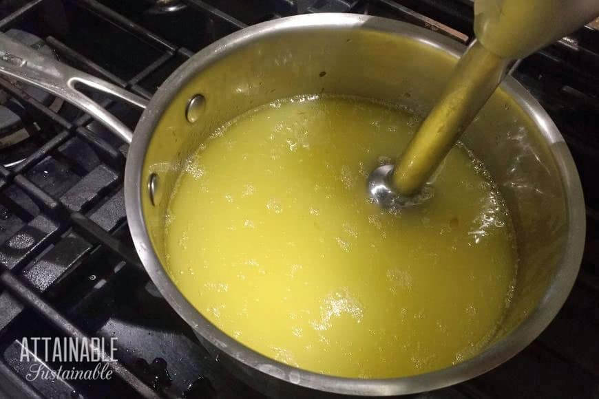 pot full of yellow liquid with an immersion blender in it.