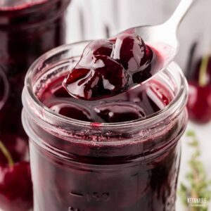 jar of cherry preserves with a spoonful being dipped out.