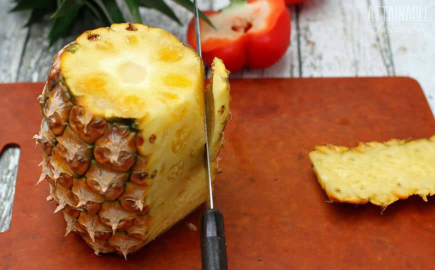 slicing the skin from a pineapple