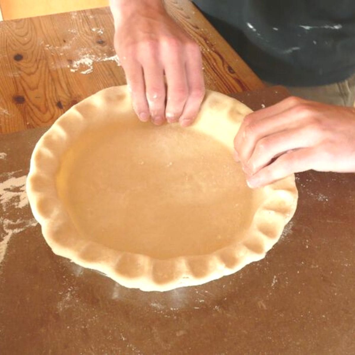 hands crimping a pie crust.