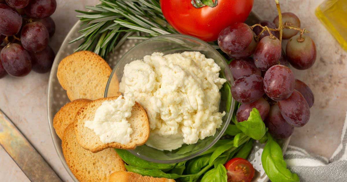 homemade ricotta cheese on a platter with toasted bread and grapes