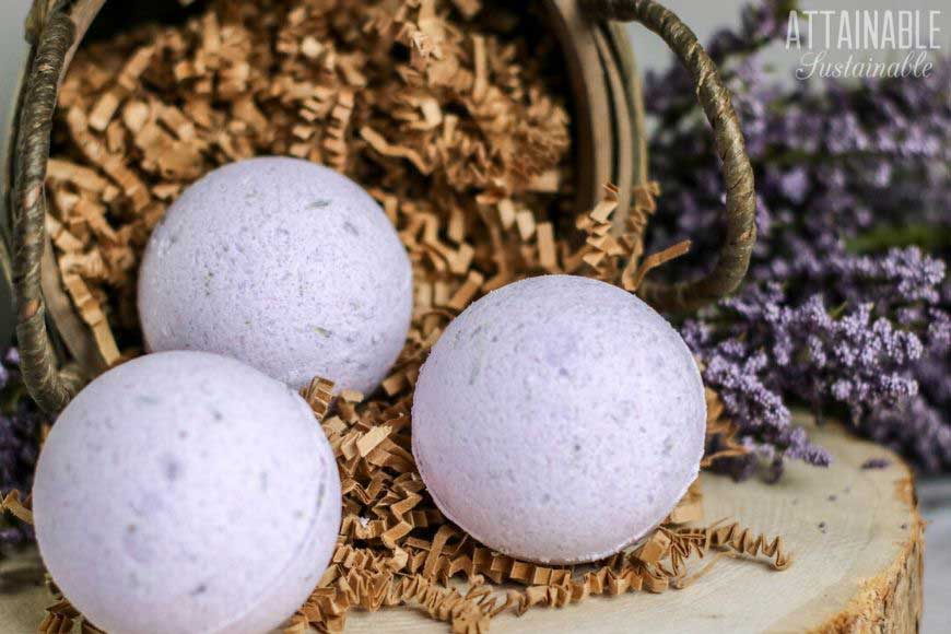 round purple bath bombs in a basket with shredded paper