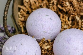 round purple bath fizzy in a basket with shredded paper