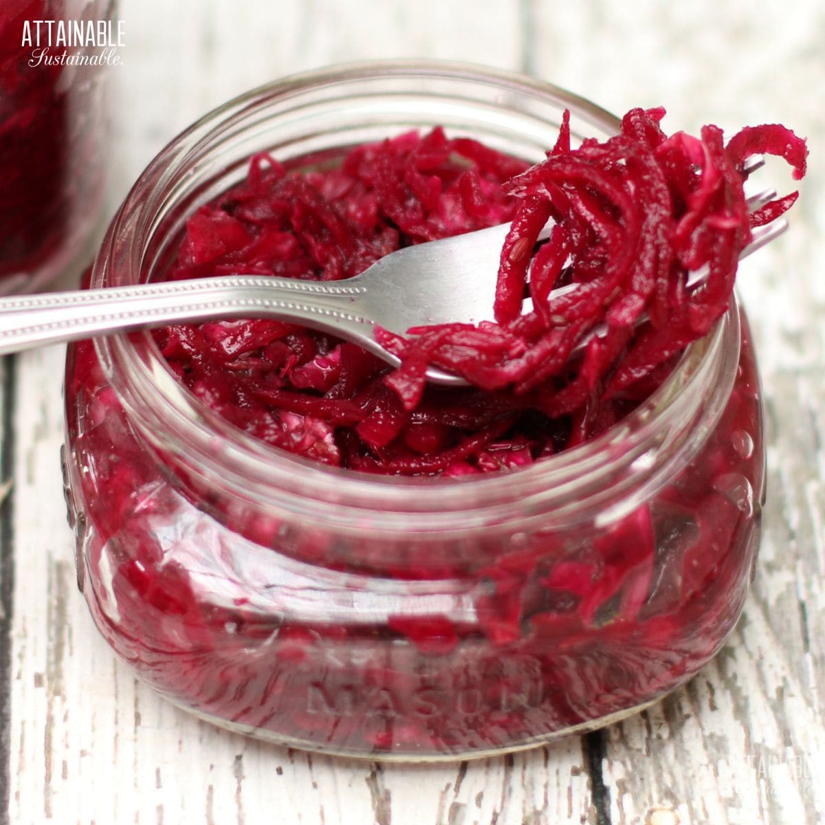 jar of bright red kraut, with strands of shredded beets and cabbage on a fork.