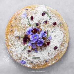 round cookie topped with purple edible flowers.