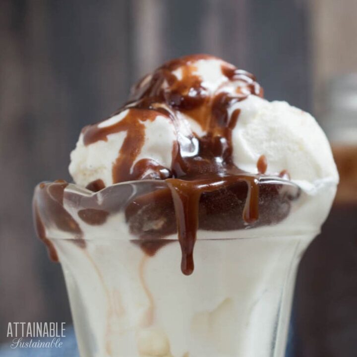 vanilla ice cream topped with hot fudge in a tall glass dish.