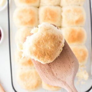 pull apart roll on a wooden spatula with a pan full in the background
