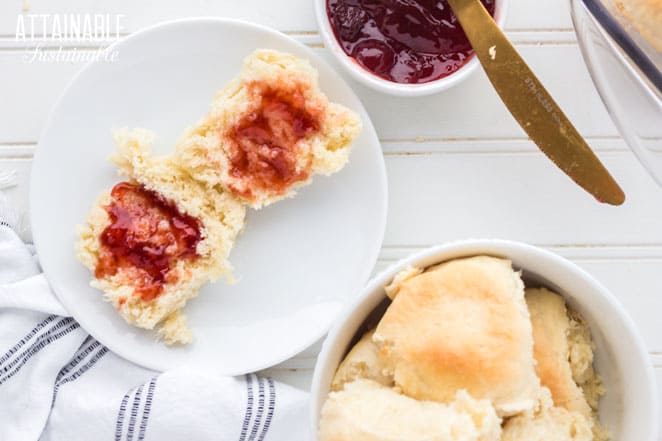 freshly baked roll on a plate, halved and spread with jam