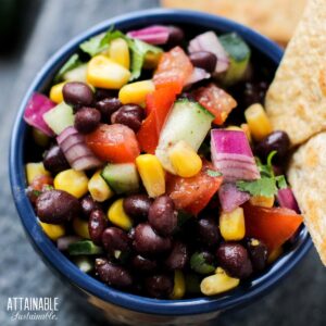 black bean dip with whole beans, corn, and veggies in a blue bowl.