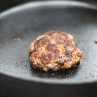 cooked sausage patty in a cast iron pan