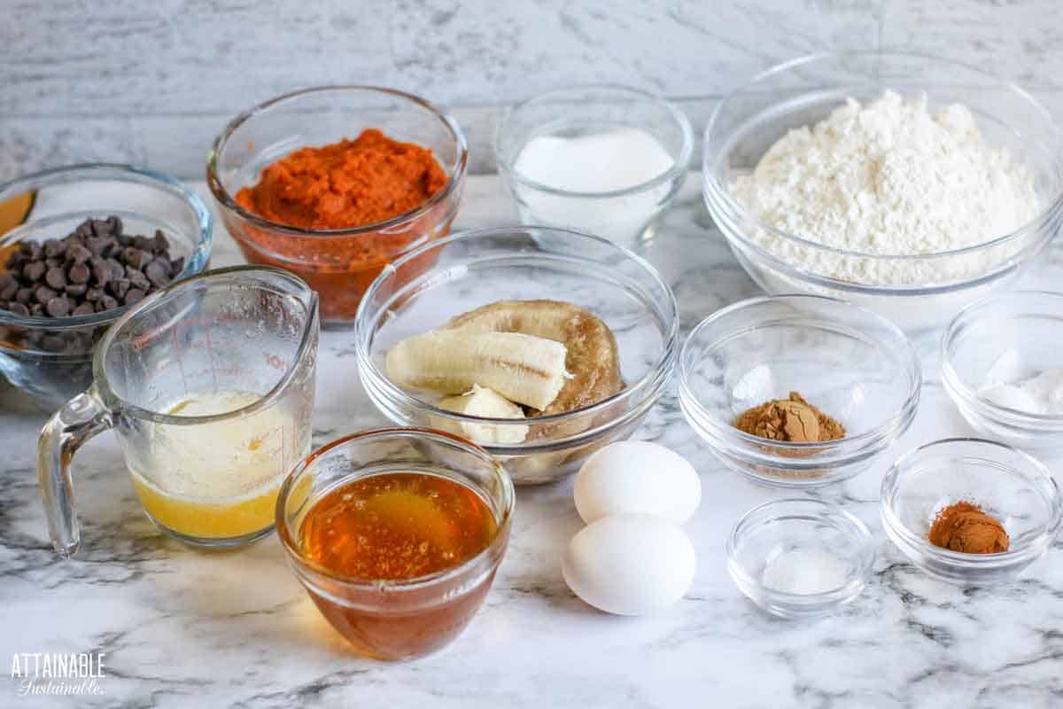 ingredients for making pumpkin banana muffins on a marble backdrop.