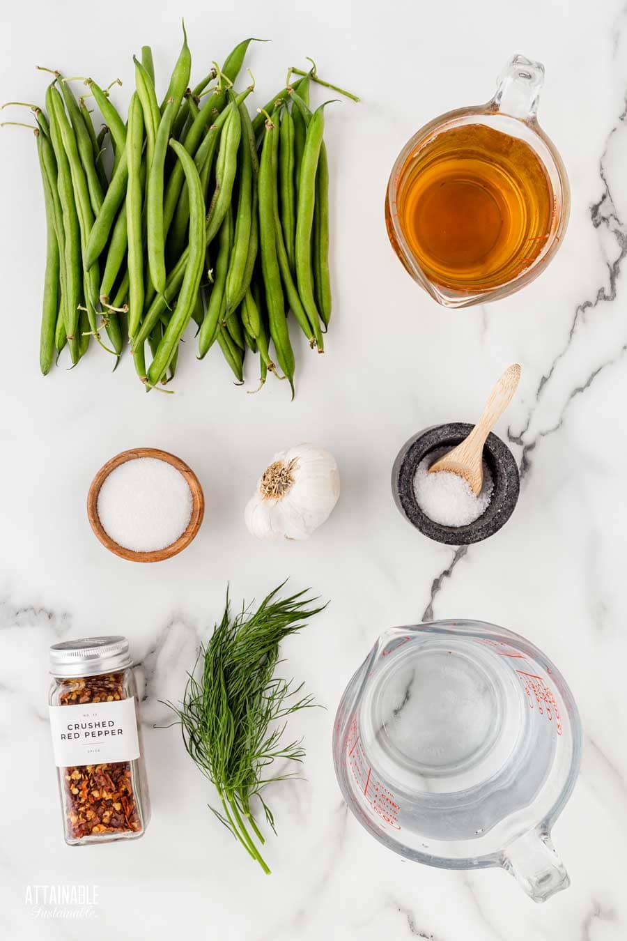 ingredients for making quick pickled green beans on a marble surface.
