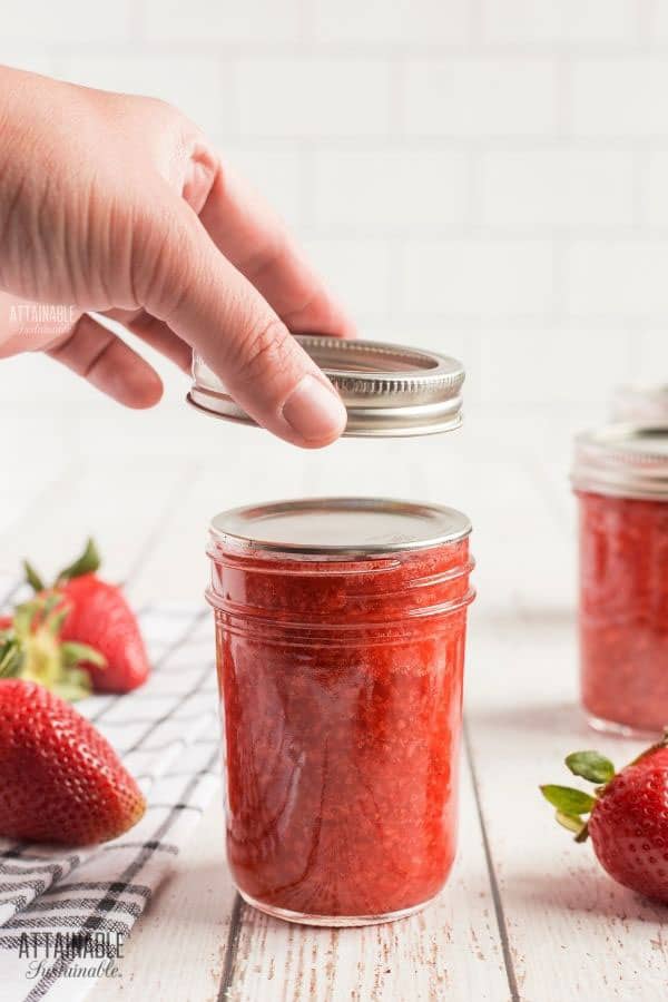 hand setting canning ring onto jar full of jam