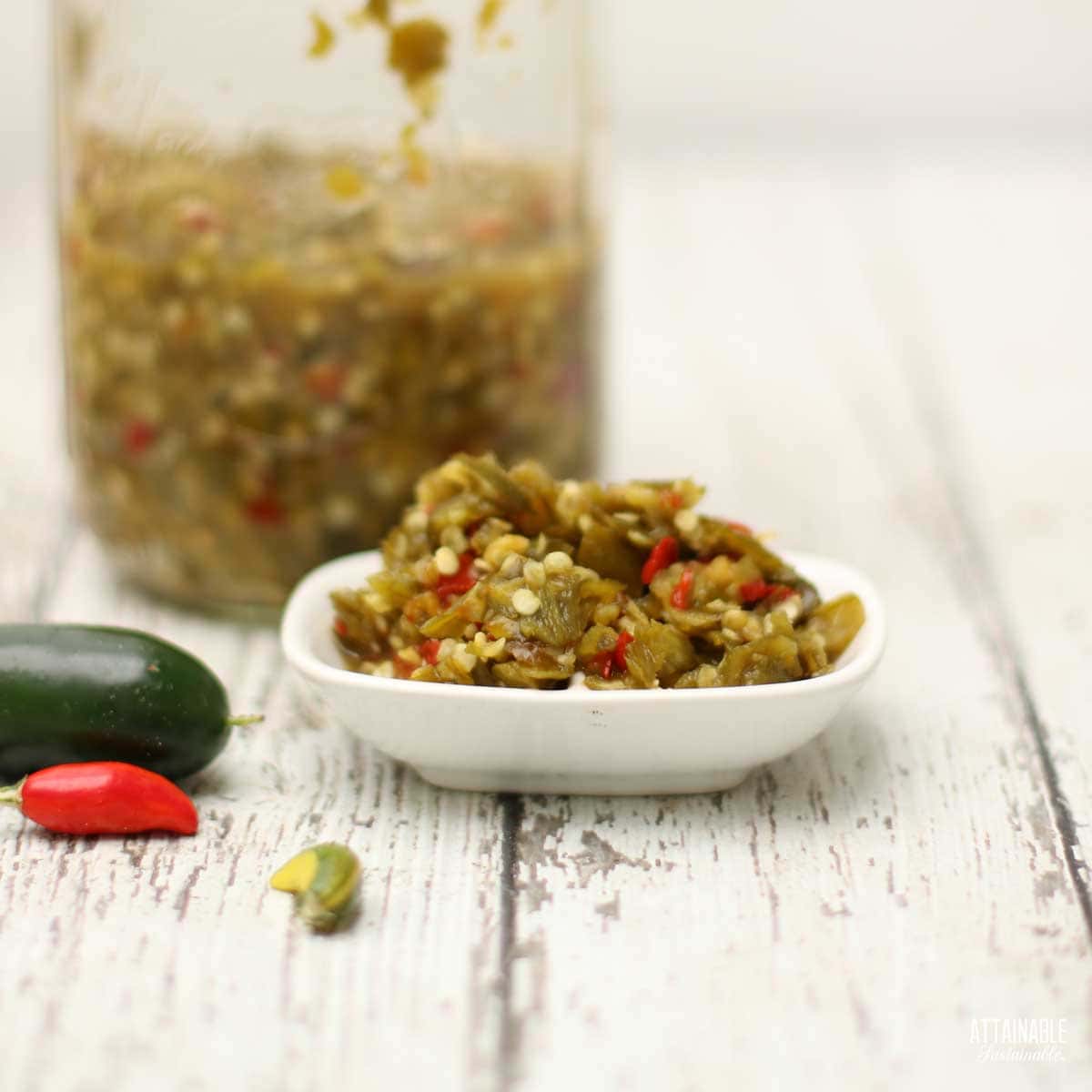 white tray with green hot pepper relish, glass jar with more behind