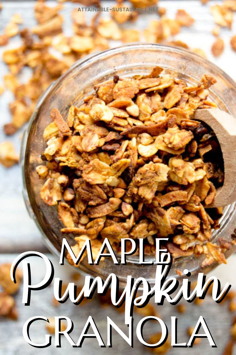 close up of pumpkin granola in a glass jar with a wooden scoop.
