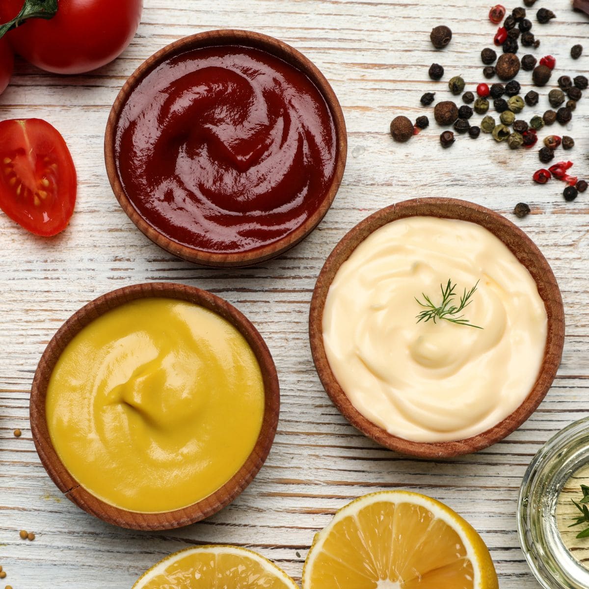 ketchup, mustard, and mayo in small brown bowls from above.
