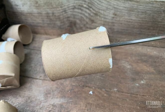 scissors cutting a notch in a cardboard tube