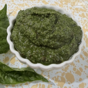 small scalloped white dish filled with dark green pesto.
