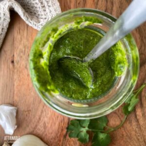 cilantro sauce in a jar with a spoon.