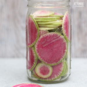 pink and green slices of a watermelon radish in a jar.