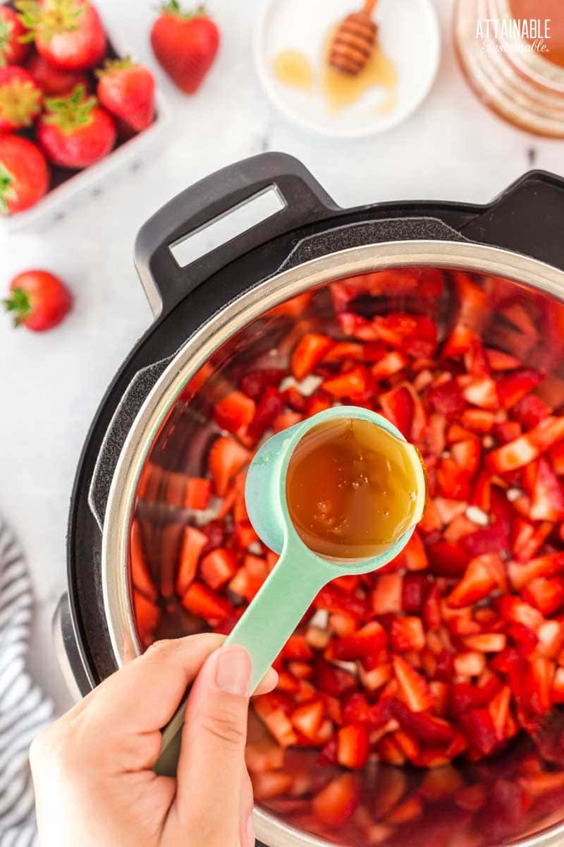 adding honey to strawberries in an electric pressure cooker.