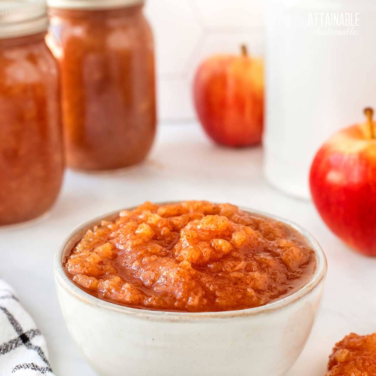 bowl of chunky applesauce, jars in background.