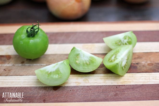 green tomato quartered on a cutting board