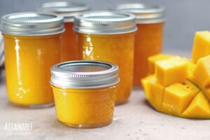 jars of mango jam with a sliced fresh mango