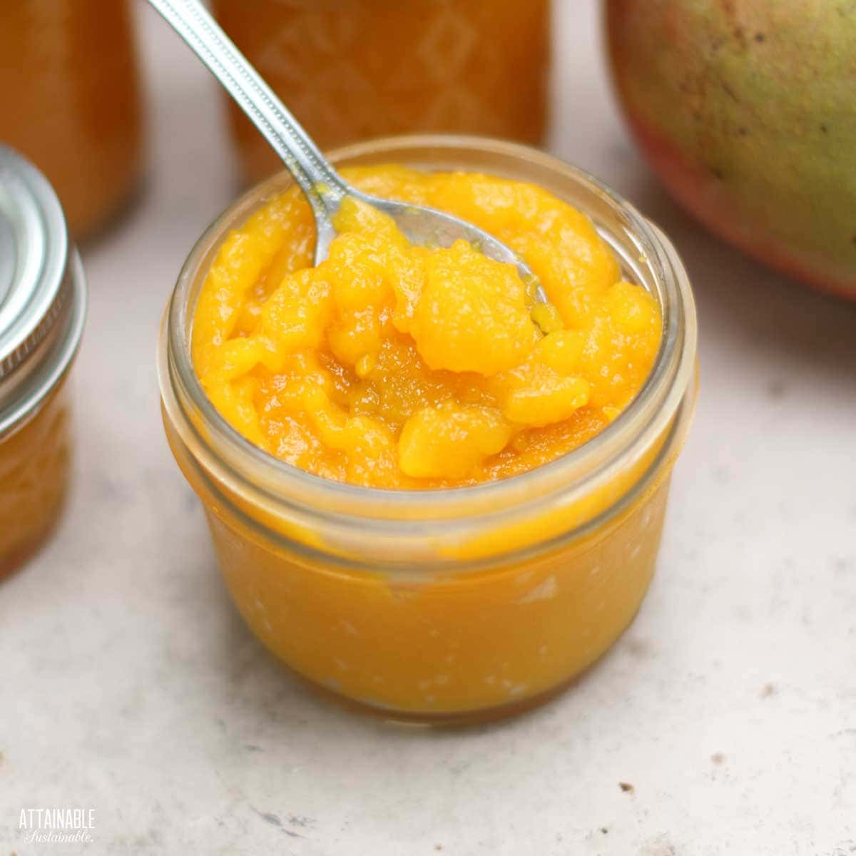 jars of mango jam, one open with a spoon in it.