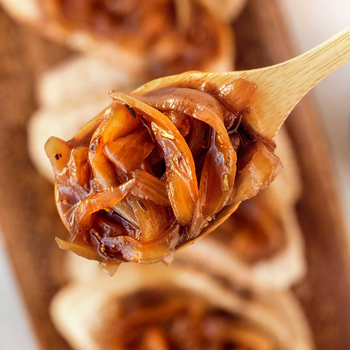 browned onions on a spoon with baguette slices in the background.