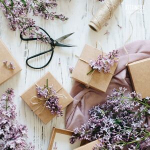 brown boxes surrounded with fresh lilacs, scissors, and twine.