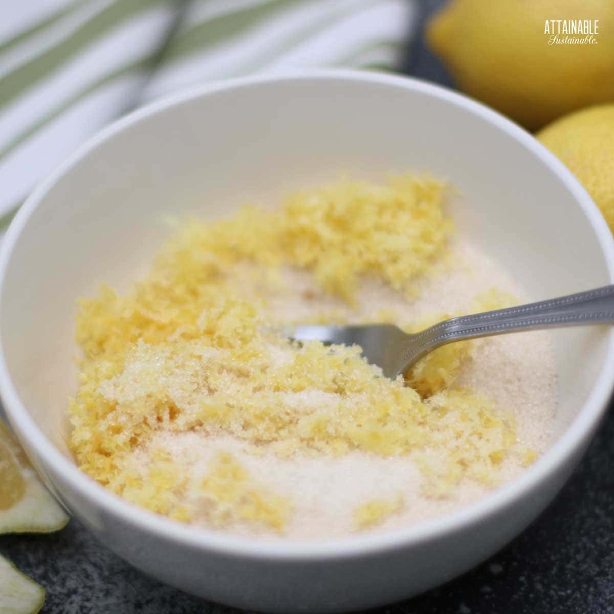 lemon zest and sugar in a white bowl with a fork.