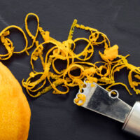 citrus zester on a black background with orange and zest