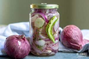 glass jar with red onions and a sliced hot pepper