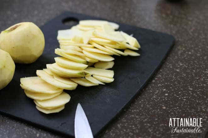 thinly sliced apples on a black cutting board