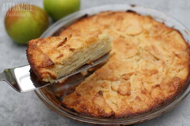 french apple cake in a pie pan, one slice on a serving utensil