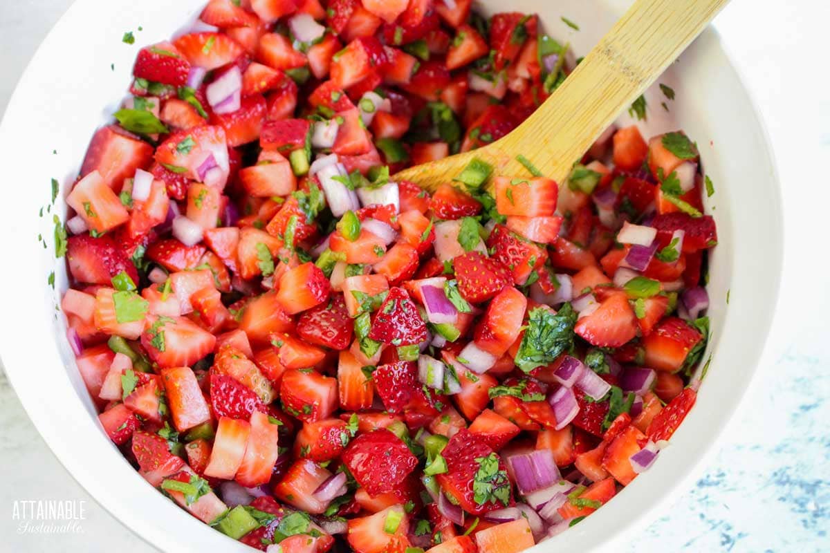 wooden spoon mixing strawberry salsa.