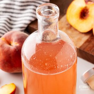 peach syrup in a jar with sliced peach alongside.