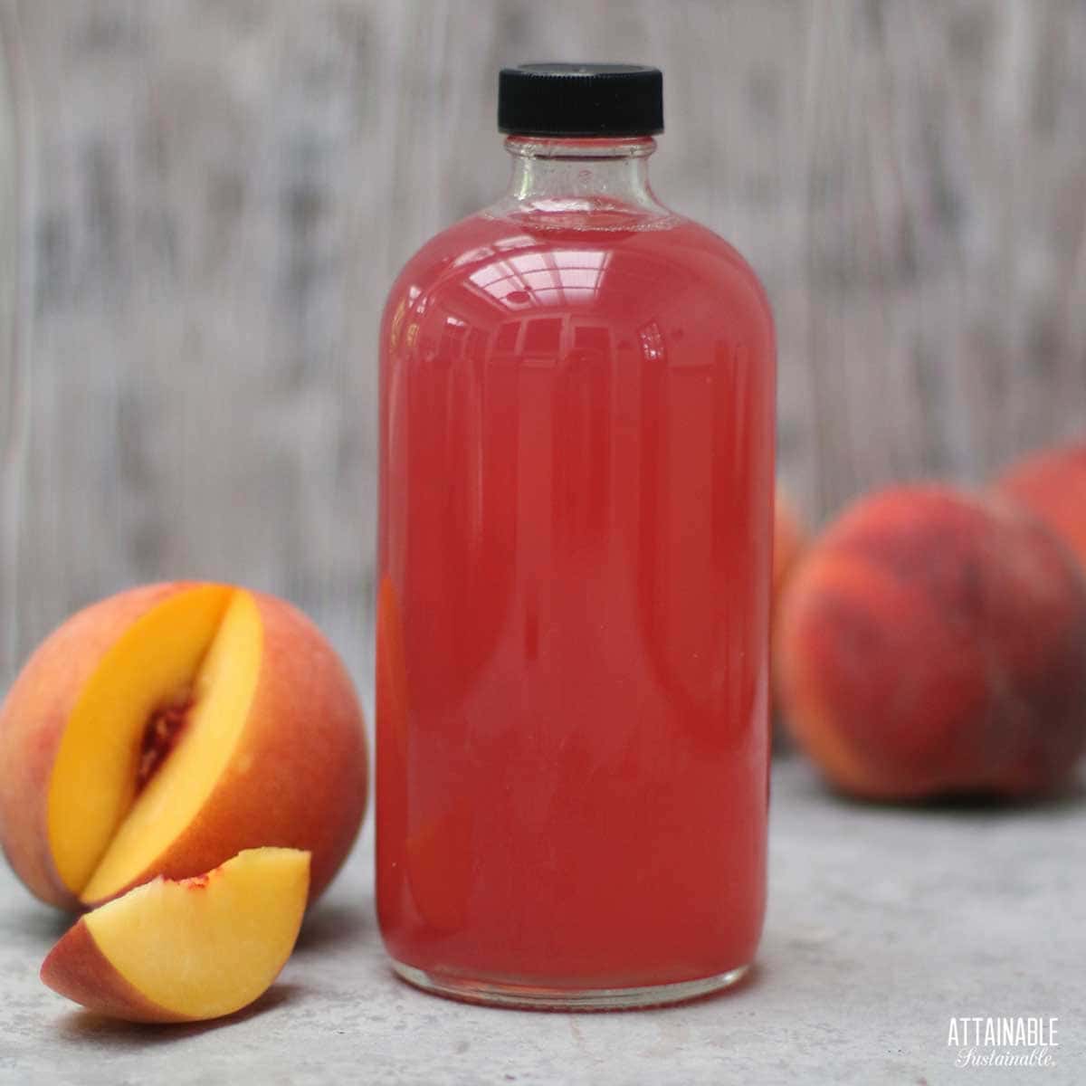 peach syrup in a jar with sliced peach alongside.