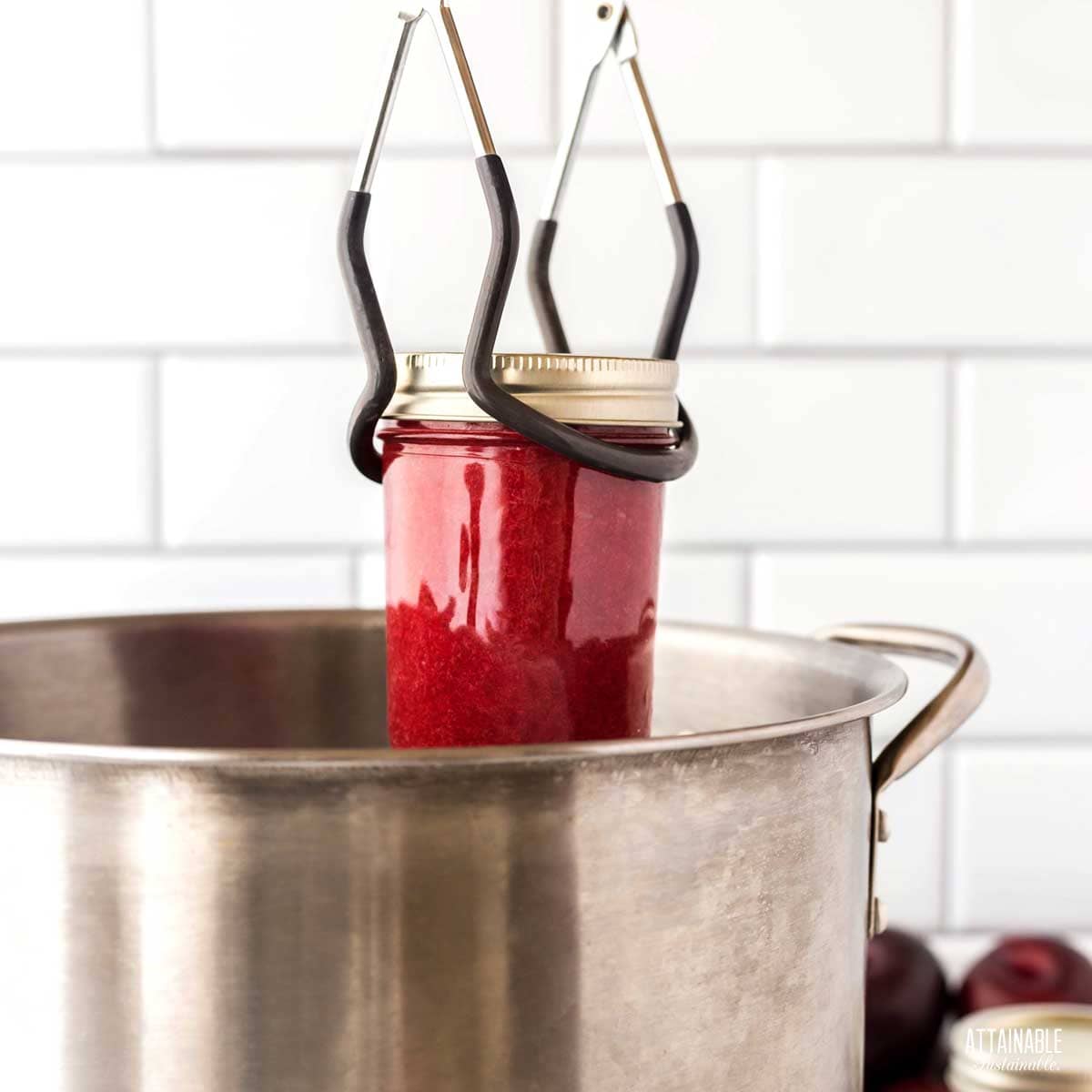 placing a jar of jam into a water bath.