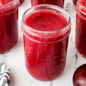 jars of plum jam with lid off.