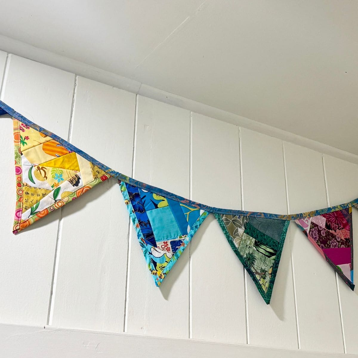 colorful fabric bunting made of upcycled fabric on a white wall.