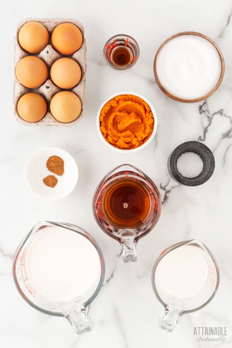 ingredients for making pumpkin custard cups on a marble background.