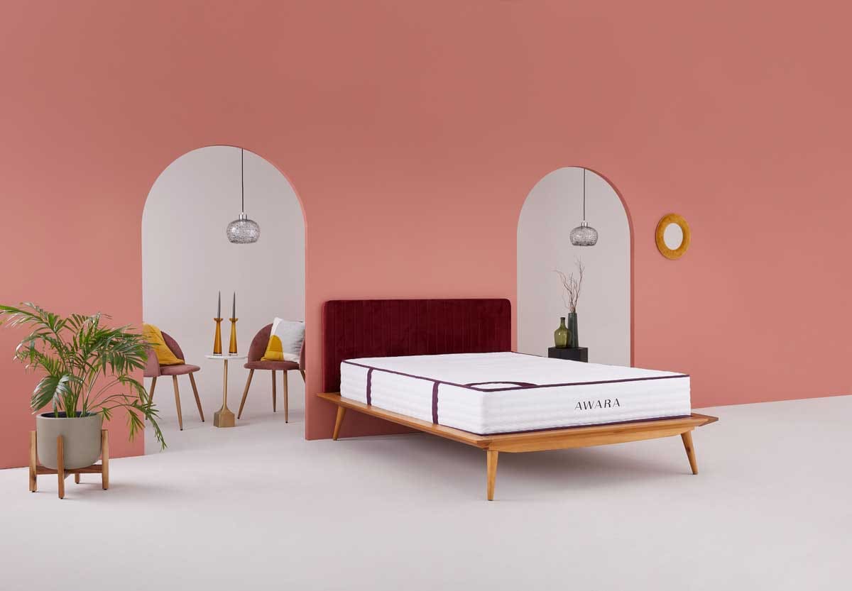 mattress with no linens on a wooden frame.