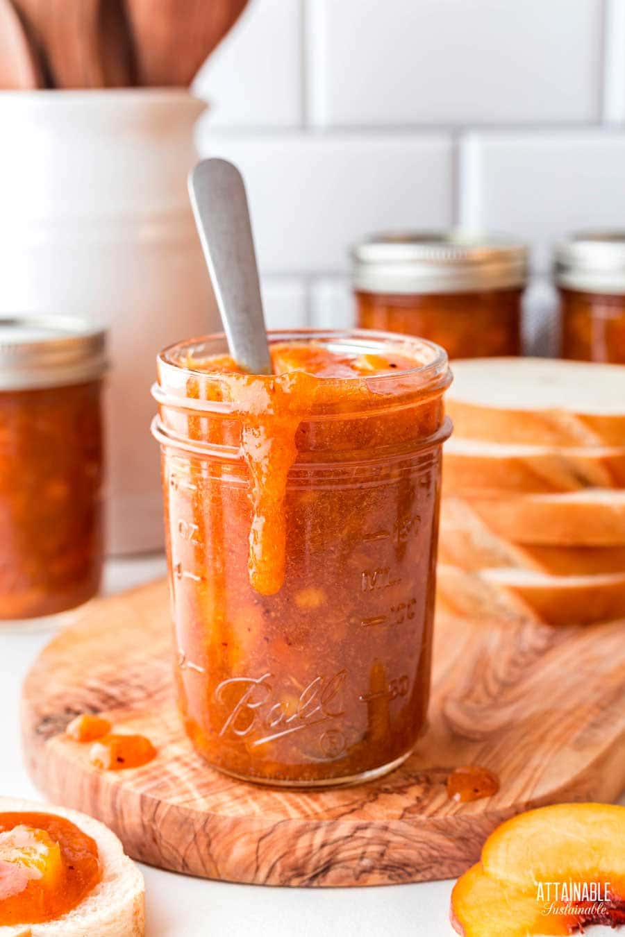 peach jam with spoon in the jar, spill down the side.