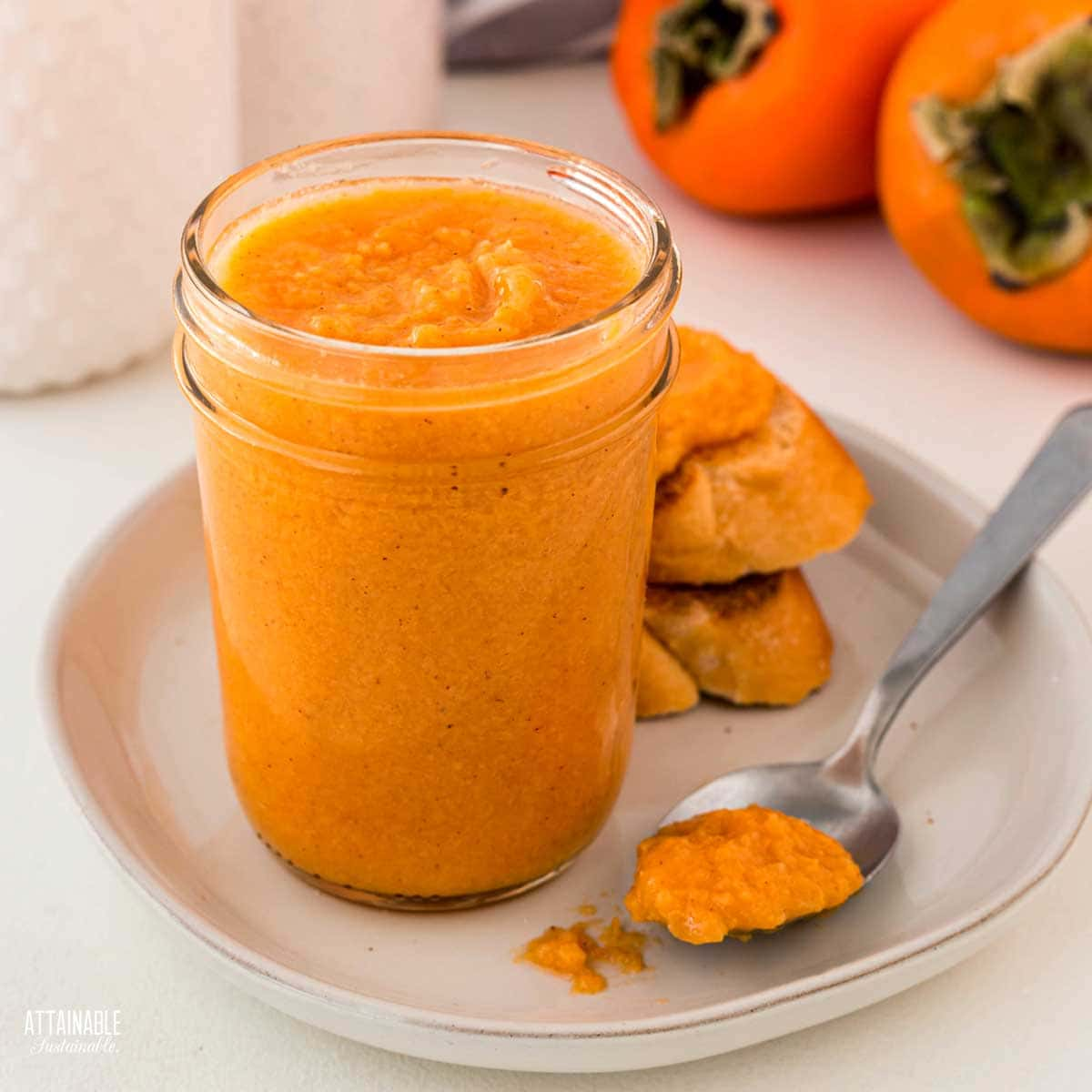 jar of persimmon jam with a spoonful and toast.