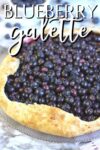 Blueberry galette close up with a golden crust, and white writing on top reading blueberry galette.